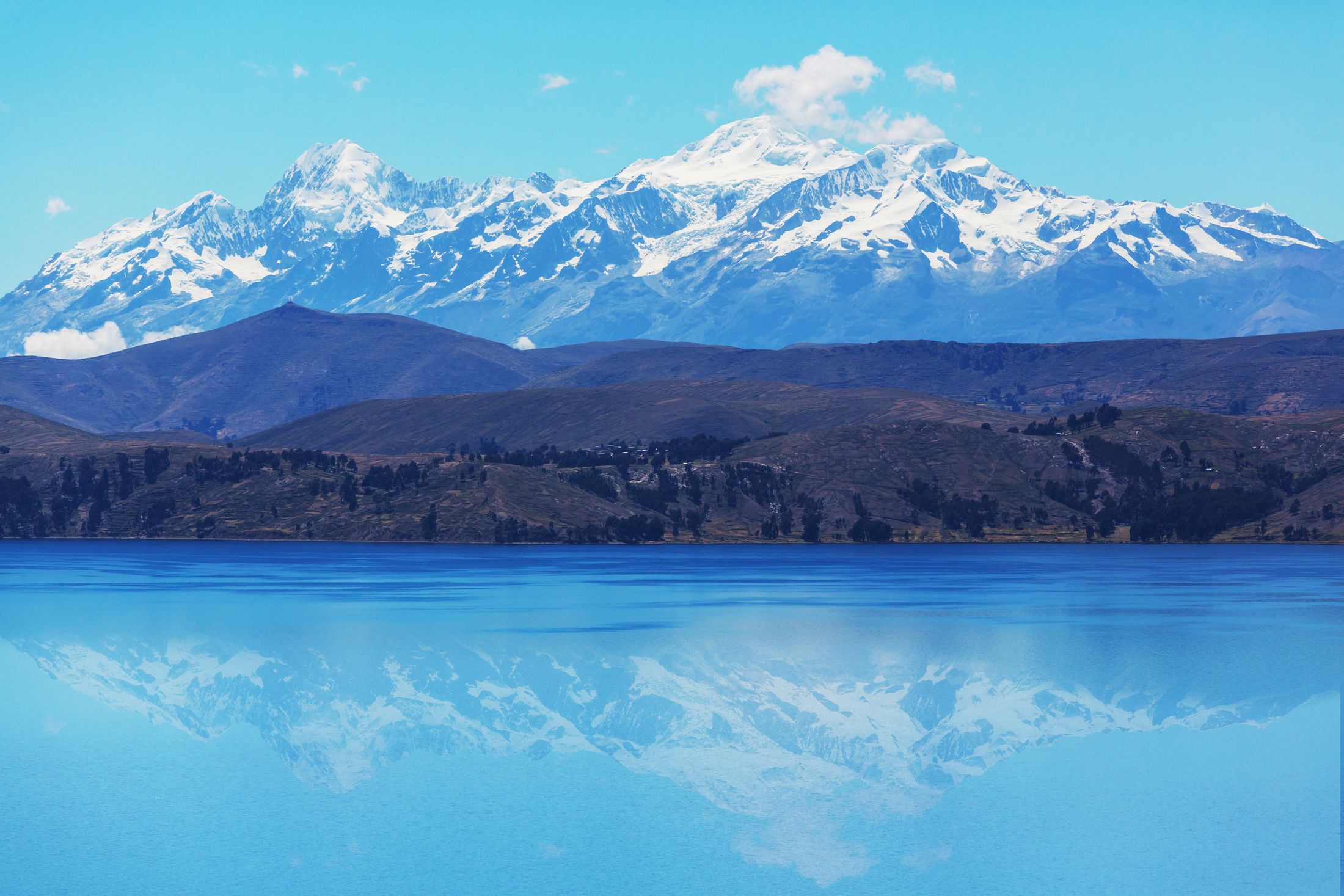 Lake Titicaca at dawn, snow-capped mountains reflected in still water